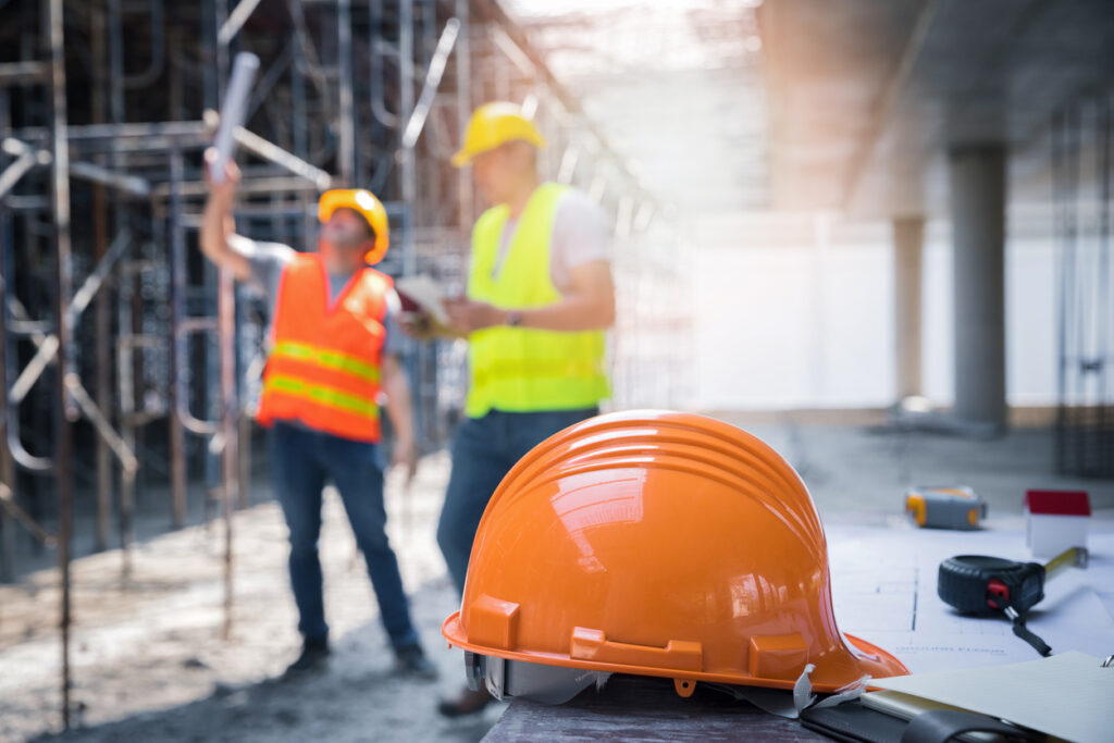 Construction hat on a building site in front of construction workers